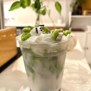 Matcha latte with ube syrup topped with whipped cream and cereal