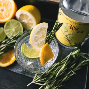 a bottle of wildwood gin with lemons and rosemary