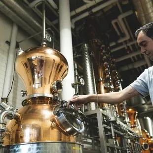 a man standing in front of a copper vessel