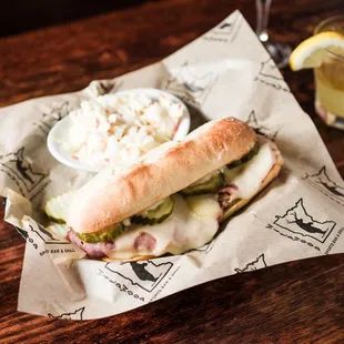 New Cuban Philly - Pulled Pork and shaved ham with thick sliced pickles, melted swiss cheese with cumin-lime aioli sauce on a hoagie bun.