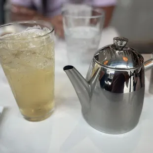 a silver teapot and a glass of lemonade