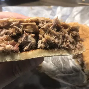 a hand holding a pulled pork sandwich