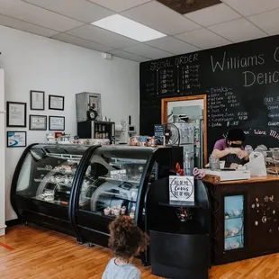 a little girl standing in front of a bakery counter