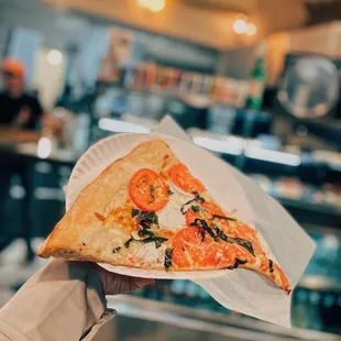 a hand holding a slice of pizza