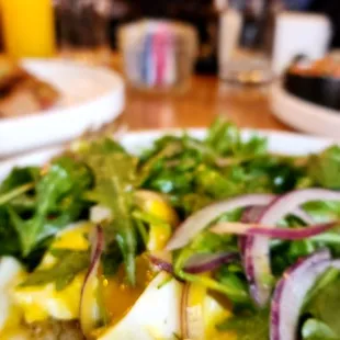 Arugula salad over avocado toast with poached eggs.