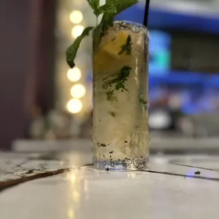 a tall glass of mojita on a bar