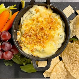 a bowl of dip with chips, carrots, and grapes