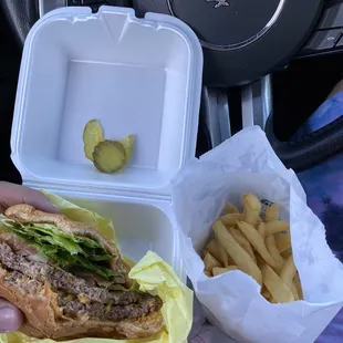 a hand holding a sandwich and french fries