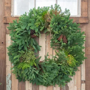 A mixed wreath made of fraser fir, boxwood, and cedar with pine cones