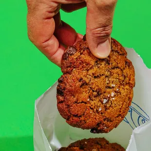 a hand picking a cookie from a bag