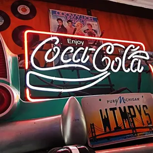 a neon coca cola sign on the back of a car