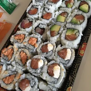 a tray of sushi rolls with avocado and salmon