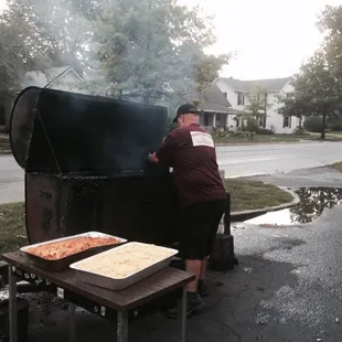 The owner putting a tray of mac n cheese into the smoker -yum!