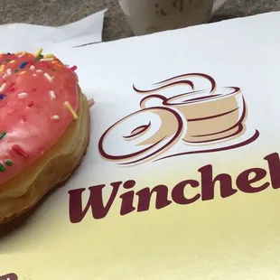 a pink frosted donut with sprinkles
