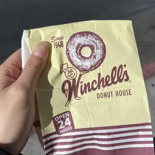 a hand holding a bag of doughnuts