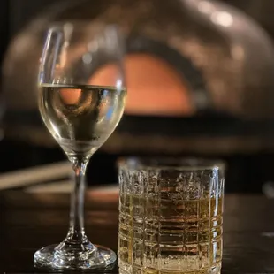 a glass of wine next to a brick oven