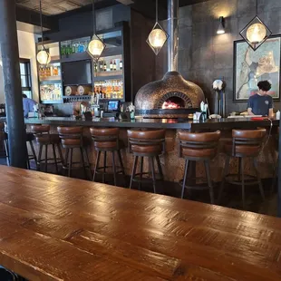 a bar with a brick oven in the background