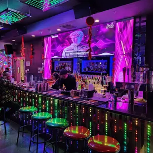 a bar with neon lights and bar stools
