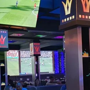 people watching a soccer game on tv screens