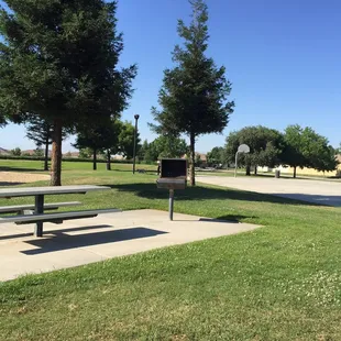 A table with barbecue grill next to the basketball court.