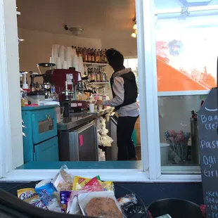 a woman standing in the window of a coffee shop