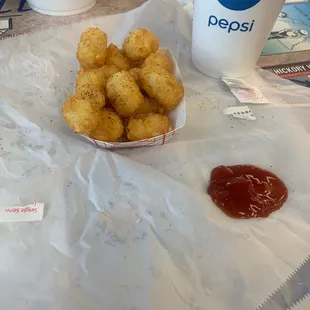 a tray of tater tots and a cup of pepsi