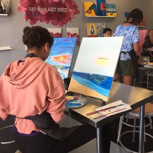 A wonderfully talented artist painting a beach sunset during a pop in and paint