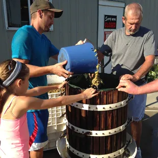 a group of people pouring wine into a barrel