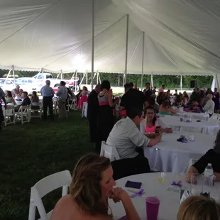 a large group of people sitting at tables under a tent