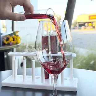 a person pouring red wine into a glass