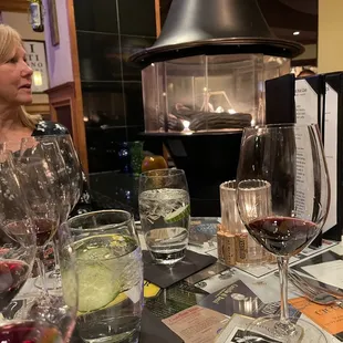a woman sitting at a table with wine glasses