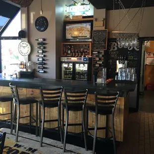 a bar with stools and a clock on the wall