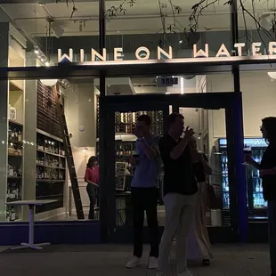 people standing outside a wine shop