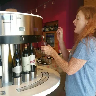 a woman standing in front of a wine dispenser