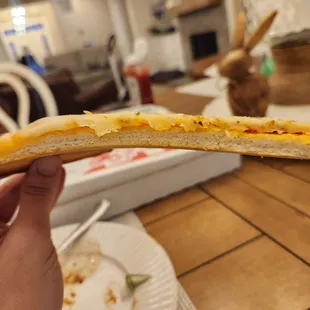 a person holding a piece of bread with cheese on it