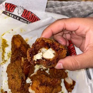 a hand holding a fried chicken