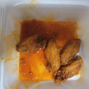 chicken wings and sauce in a styrofoam container