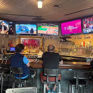 people sitting at the bar watching tvs