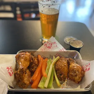 a tray of wings, carrots, celery, and a glass of beer