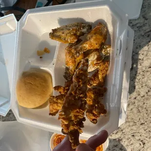 chicken wings and a roll in a styrofoam container