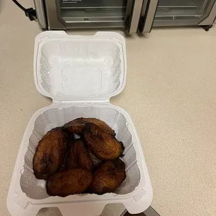 a container of fried bananas in front of a toaster oven