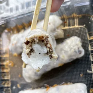 a person holding chopsticks over a tray of food