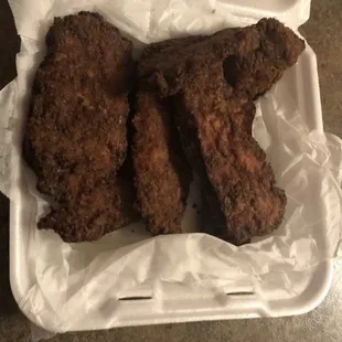 two pieces of fried chicken in a plastic container