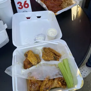 a tray of chicken wings, celery sticks, and sauce