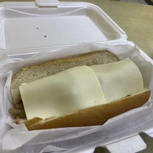 Small cheesesteak served with cold pieces of cheese on top.