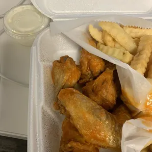 chicken wings and fries in a styrofoam container