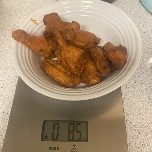 a bowl of fried chicken on a scale