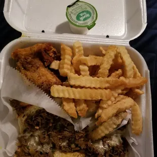 a sandwich and french fries in a styrofoam container