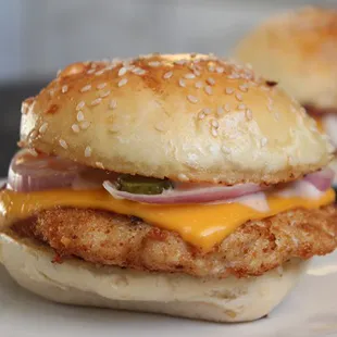 two chicken burgers with cheese and pickles