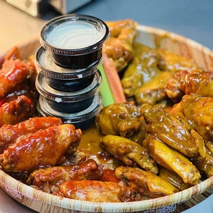 a wooden bowl of wings and hot sauce